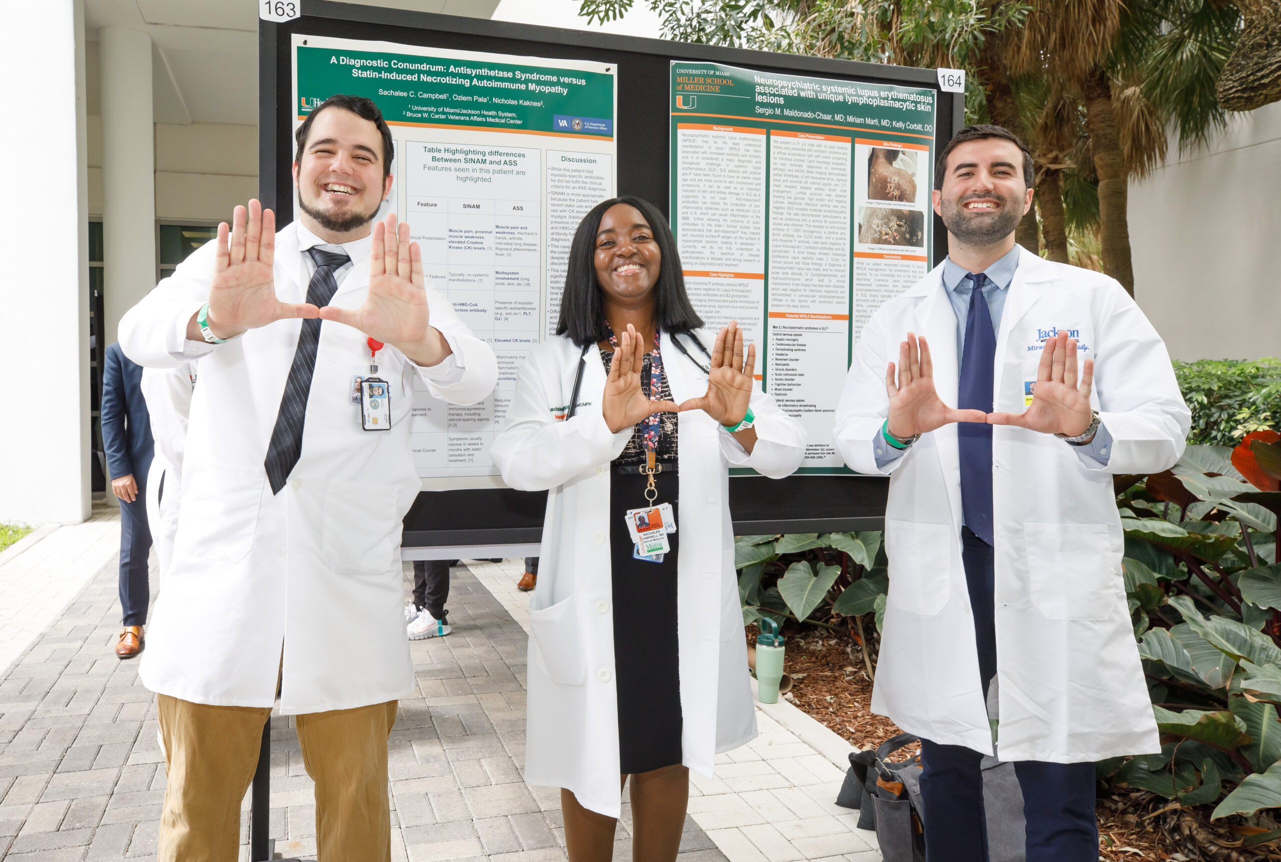 Three learners standing in front of research posters.